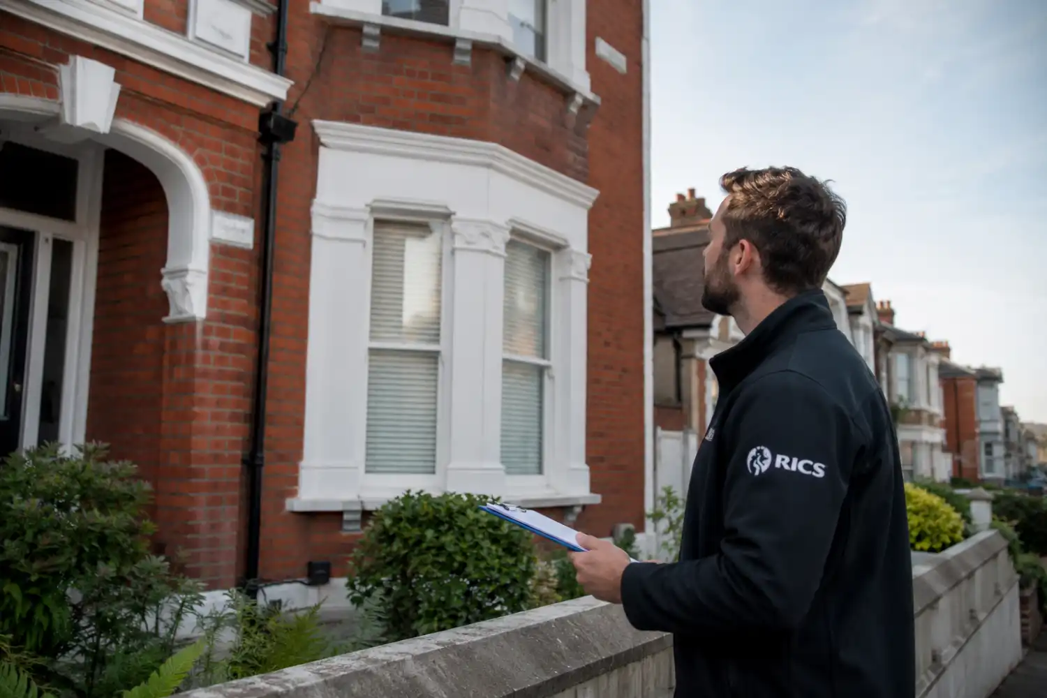 bridging loan valuation process — RICS surveyor with clipboard inspecting UK property exterior